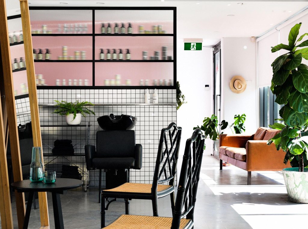 inside of a salon with hair wash area and waiting room. Chairs and products.