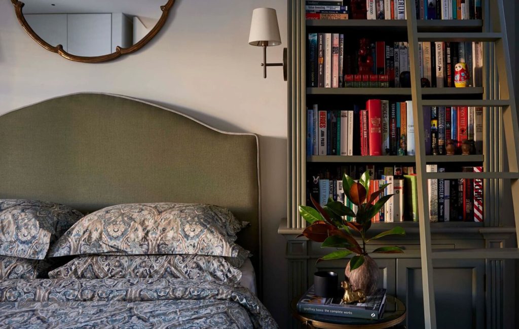 Classic bedroom with green headboard and built-in bookshelf and ladder.