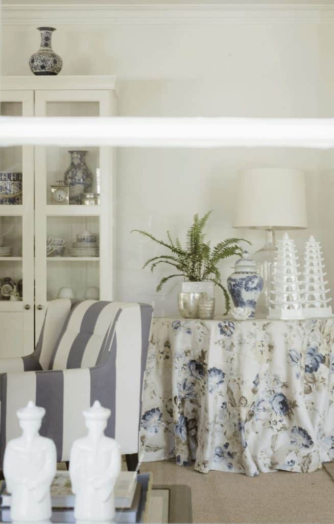 Classic blue and white sitting room with striped armchair and floral skirted table. Discover timeless home decor.