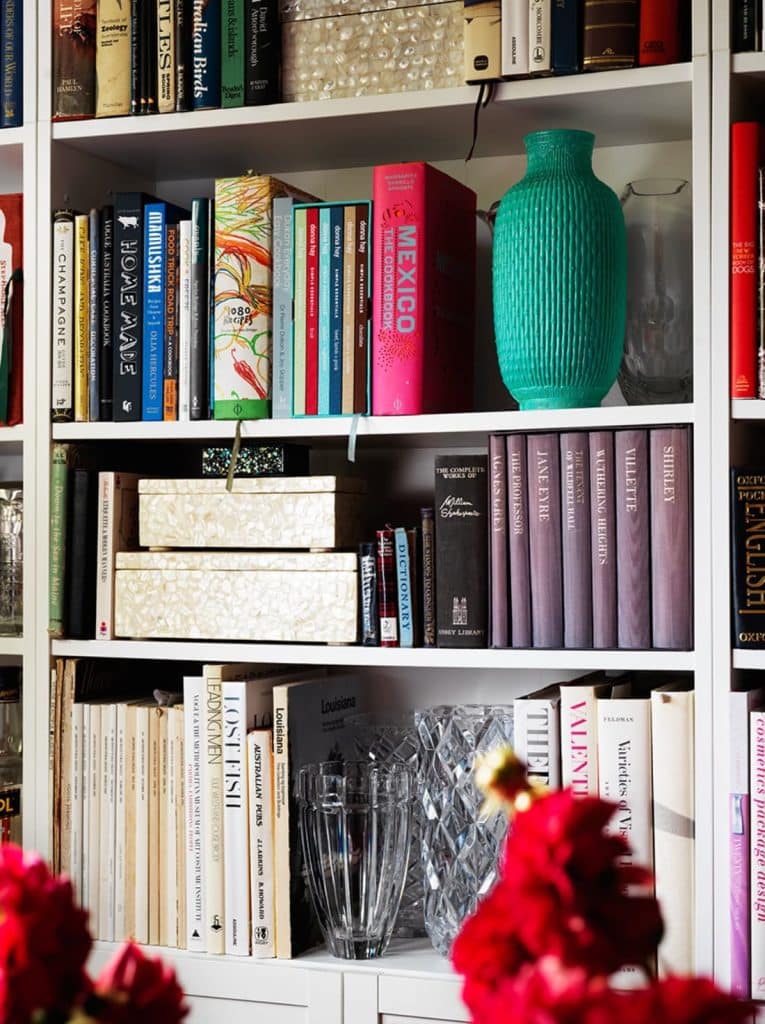 Close-up of colourful books and ornaments on a well-styled bookshelf.