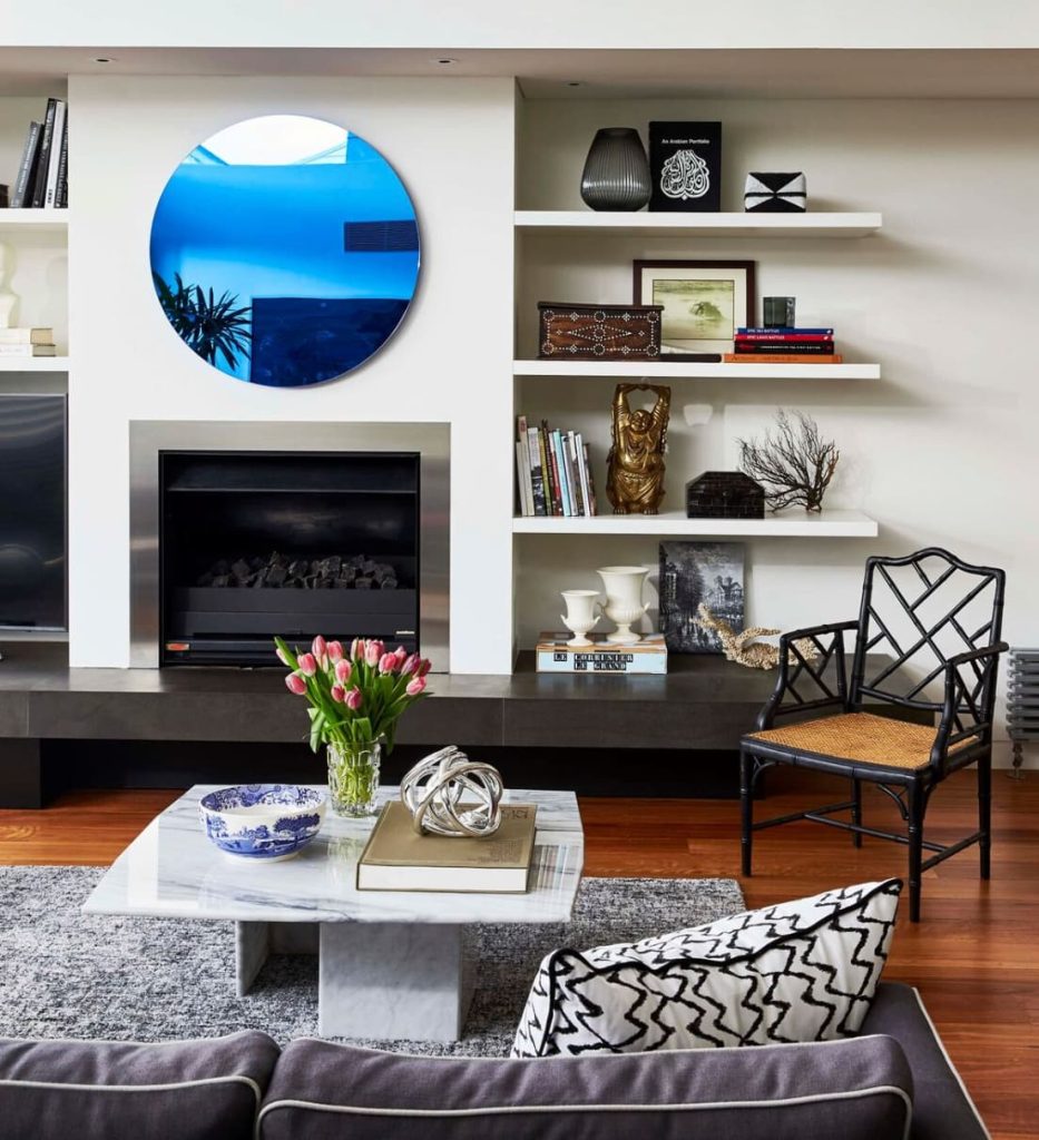 Modern living room with blue mirror, fireplace, and eclectic decor.