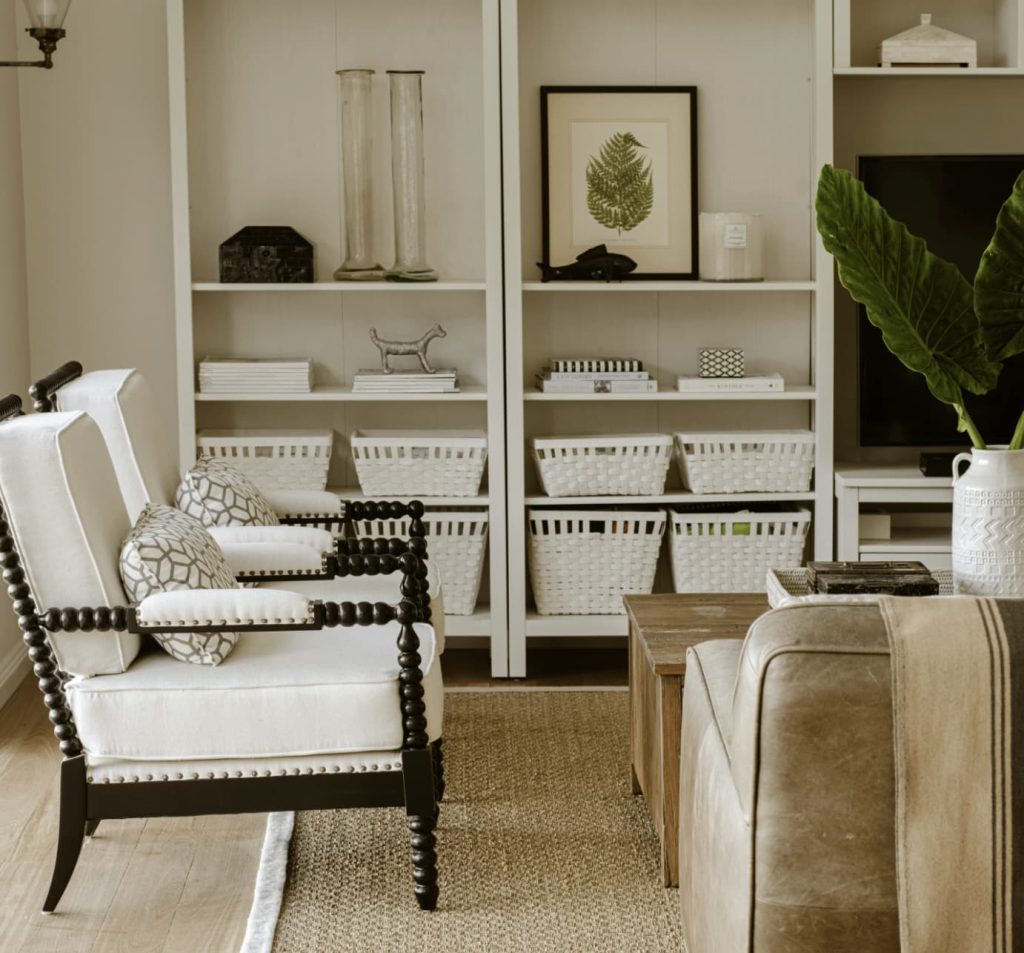 White armchairs and built-in shelves in a neutral-toned cosy living room.