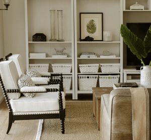 White armchairs and built-in shelves in a neutral-toned cosy living room.