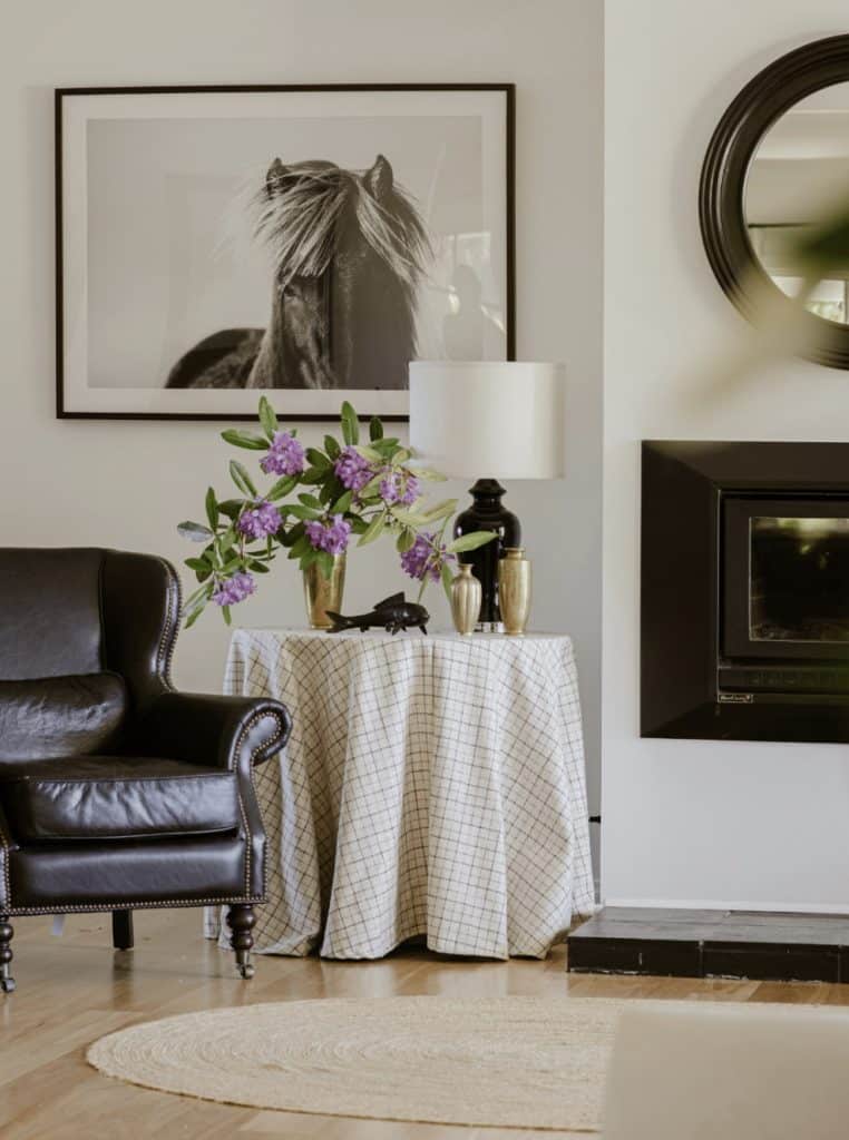Stylish living room with black leather chair, horse artwork and floral details by Gabriel Jacka