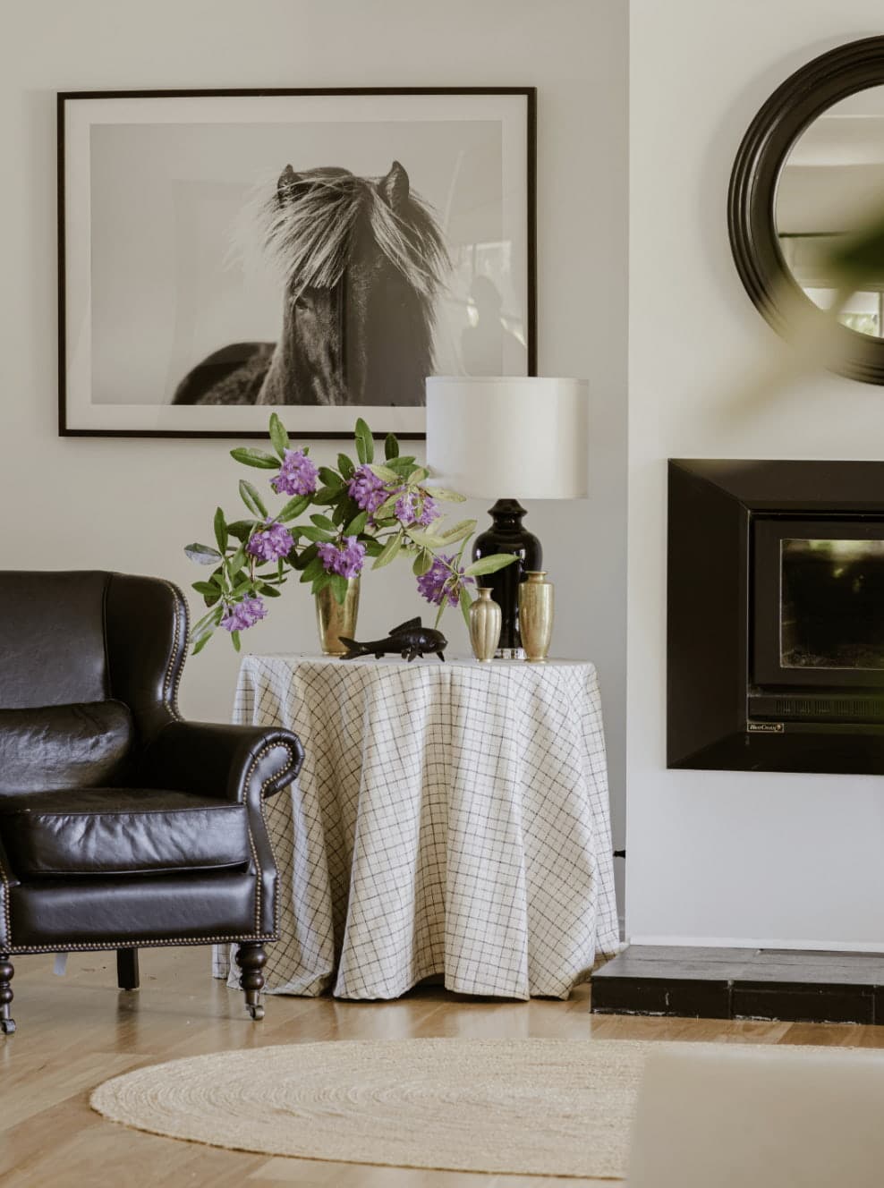 Stylish living room with black leather chair, horse artwork and floral details by Gabriel Jacka