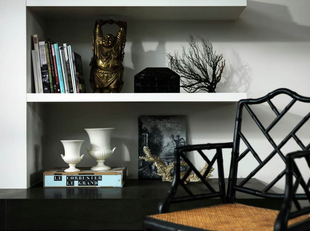 Modern shelves with eclectic decor, books and black chair styled by Gabriel Jacka