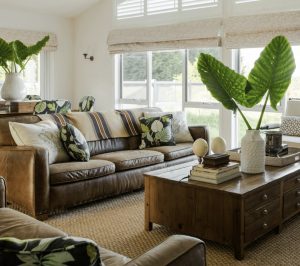 Leather sofa with botanical cushions and large leaf decor styled by JACKA DESIGN